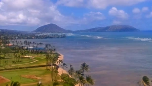 Beautiful view of the coastline's breaking waves and lush, green vegetation at the base of Diamondhead in Oahu, Hawaii.