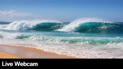 A large, windblown wave breaks on a golden sand beach in Oahu, Hawaii.