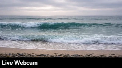 Live, close up view of the sand and surf at Carlsbad Beach in San Diego, California.