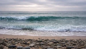 Live, close up view of the sand and surf at Carlsbad Beach in San Diego, California.