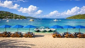 Live close up view of the picnic table area on the beach with boats moored in the bay.