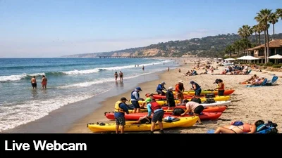 Kayakers prepare their boats while people enjoy the sun and sand at La Jolla Shores in San Diego.
