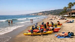 Kayakers prepare their boats while people enjoy the sun and sand at La Jolla Shores in San Diego.