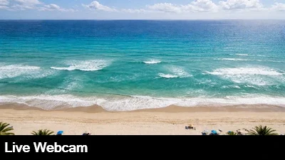 Live view looking down at the golden sand and breaking waves on the beach.