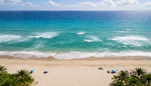 Live view looking down at the golden sand and breaking waves on the beach.