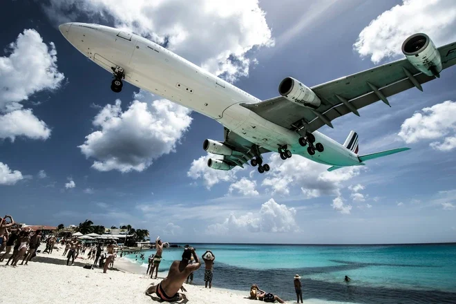 A large commercial airliner lands in St Maarten just feet above famous Maho beach