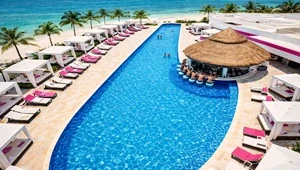 Live view from the top of the Temptation Cancun looking down on the pool, bar and cabana area with the beautiful Caribbean and boats moored next to the beach.